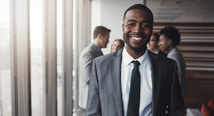 Young businessman smiling, standing in front of colleagues