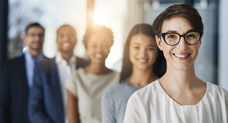 Businesswoman smiling, with line of colleagues behind her