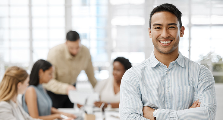 Smiling businessman with team working behind him