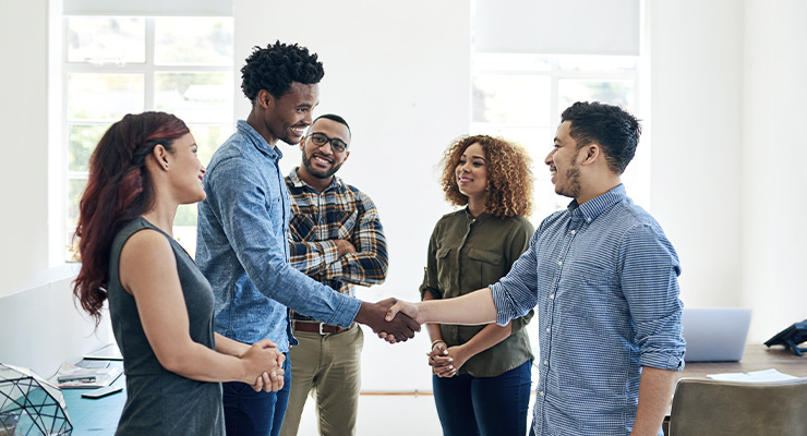 Group of young professionals smiling and shaking hands