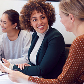 Businesswomen smiling and talking around a table