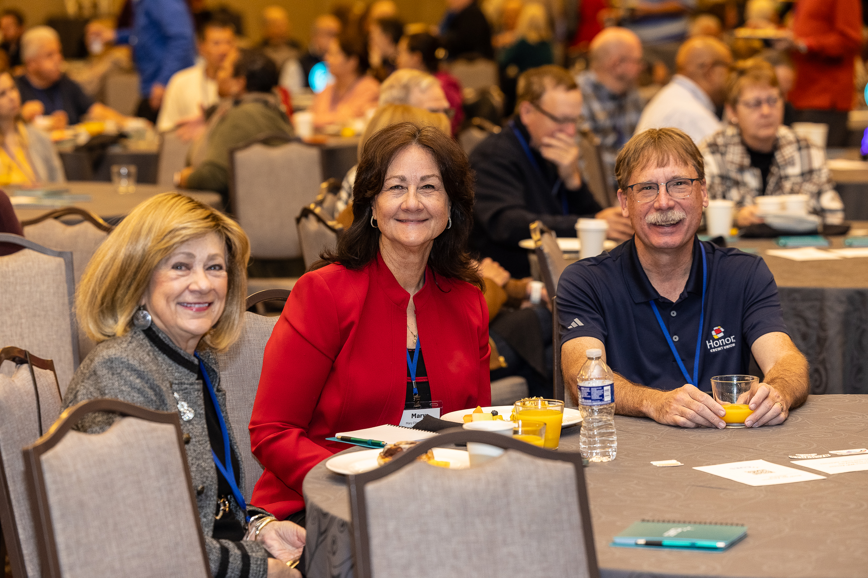 Three attendees sitting together smiling at conference table